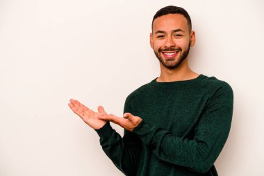 Beyaz arka planda izole edilmiş genç İspanyol bir adam avucunun içinde bir kopyasını tutuyor..