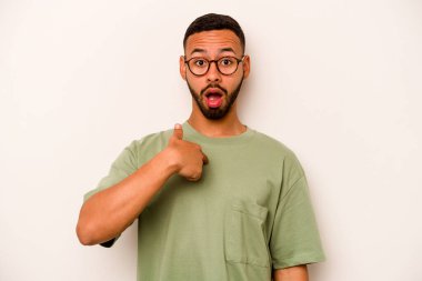 Beyaz arka planda izole edilmiş genç İspanyol adam parmağını göstererek şaşırdı, geniş bir gülümsemeyle..