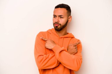 Beyaz arka plan noktalarında izole edilmiş genç İspanyol adam iki seçenek arasında seçim yapmaya çalışıyor..