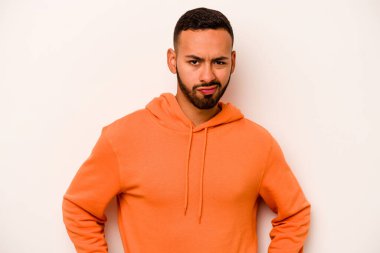 Genç İspanyol adam beyaz arka planda izole edilmiş üzgün, ciddi yüzlü, mutsuz ve hoşnutsuz..