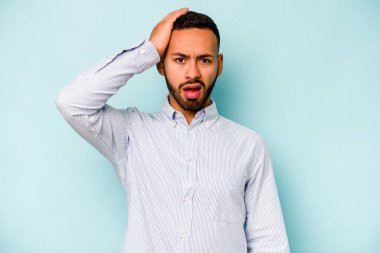 Mavi arka planda izole edilmiş genç bir İspanyol şoka uğruyor, önemli bir buluşmayı hatırlıyor..