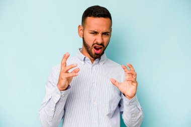 Mavi arka planda izole edilmiş genç İspanyol adam gergin elleriyle çığlık atıyor..
