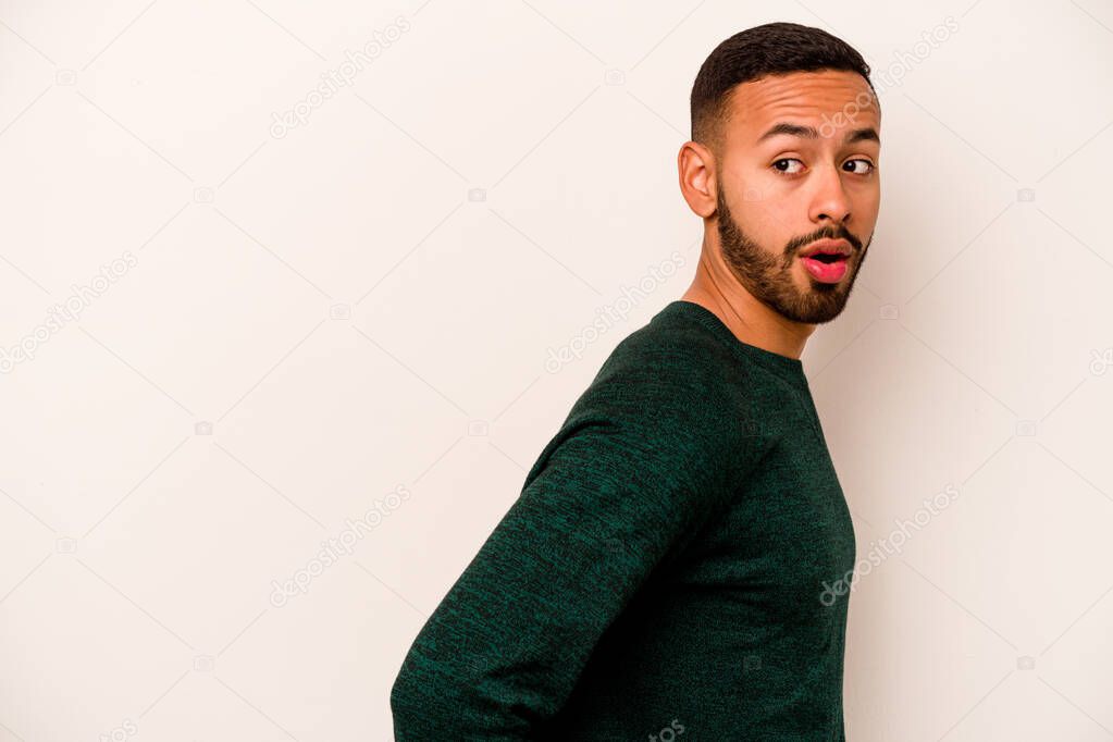 Young hispanic man isolated on white background looks aside smiling, cheerful and pleasant.