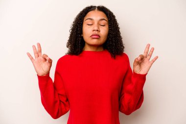 Beyaz arka planda izole edilmiş genç Afrikalı Amerikalı kadın yoğun bir günün ardından dinleniyor, yoga yapıyor..