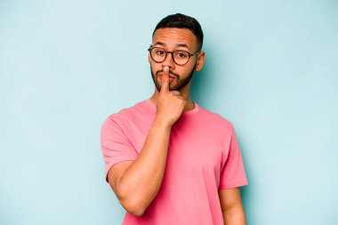 Genç İspanyol adam mavi arka planda izole edilmiş düşünüyor, bakıyor, yansıtıyor, düşünüyor, hayal kuruyor..