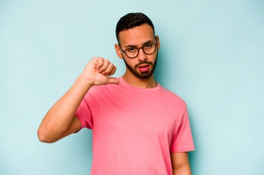 Genç İspanyol bir adam mavi arka planda izole edilmiş. Hoşlanmadığı bir hareket gösteriyor. Anlaşmazlık konsepti.