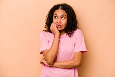 Genç Afrikalı Amerikalı kadın bej arka planda izole edilmiş tırnak yiyor, gergin ve çok endişeli..