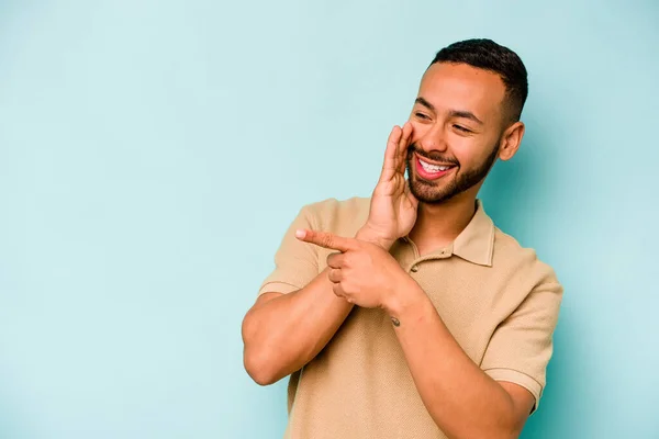 Joven Hispano Aislado Sobre Fondo Azul Diciendo Chisme Apuntando Lado —  Fotos de Stock