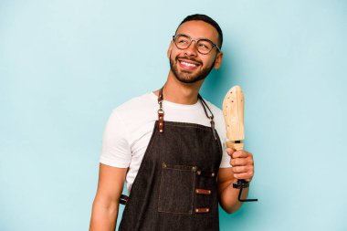 Genç İspanyol kunduracı, mavi arka planda izole edilmiş. Gülümsüyor, neşeli ve keyifli..