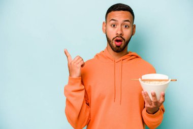 Mavi arka planda izole edilmiş erişte yiyen genç İspanyol kadın...