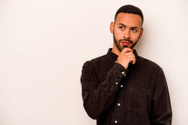 Beyaz arka planda izole edilmiş genç İspanyol bir adam rahatlamış bir şeyin fotokopi odasına baktığını düşünüyor..