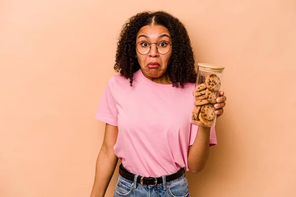 Young African American Woman Holding Cookies Jar Isolated Beige Background —  Fotos de Stock