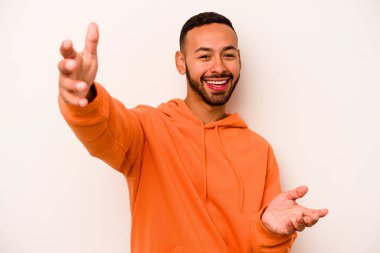 Beyaz arka planda izole edilmiş genç İspanyol adam kameraya sarıldığı için kendinden emin hissediyor..