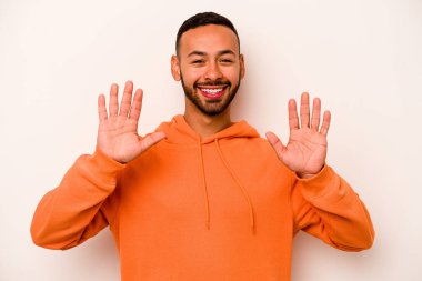 Beyaz arka planda izole edilmiş genç İspanyol adam on numarayı elleriyle gösteriyor..