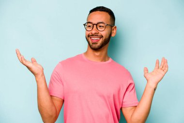 Genç İspanyol adam mavi arka planda izole edilmiş neşeli bir şekilde gülüyor. Mutluluk kavramı.