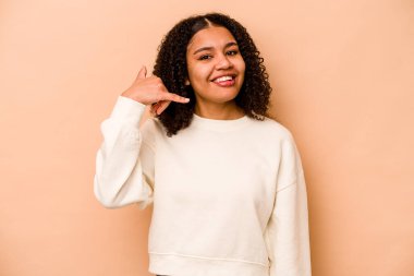 Bej arka planda izole edilmiş genç Afrikalı Amerikalı kadın parmakları olan bir cep telefonu hareketi gösteriyor..