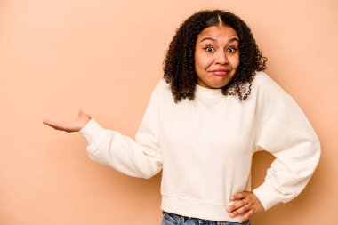 Genç Afrikalı Amerikalı kadın bej arka planda izole edilmiş bir şekilde bir avuç içinde fotokopi alanı ve belinde başka bir el tutarken görülüyor..