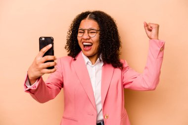 Bej arka planda cep telefonu tutan genç Afrikalı Amerikalı iş kadını