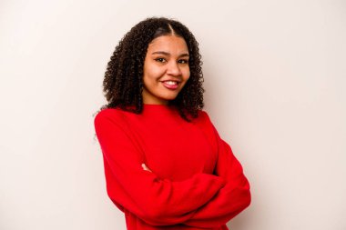 Beyaz arka planda izole edilmiş genç bir Afrikalı Amerikalı kadın. Kendini güvende hissediyor, kararlılıkla kollarını kavuşturuyor..