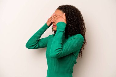 Genç Afrikalı Amerikalı kadın, beyaz arka planda izole edilmiş. Gözleri elleriyle kapamaktan korkuyor..