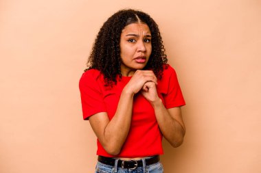 Genç Afrikalı Amerikalı kadın bej arka planda izole edilmiş korkmuş ve korkmuş..