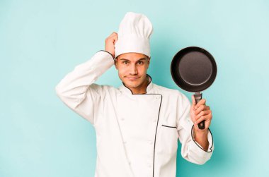 Kafkasyalı genç aşçı elinde uçan bir tavayla mavi arka planda mahsur kaldı..