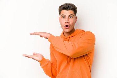 Beyaz arka planda izole edilmiş genç beyaz adam elleri arasında bir kopya alanı tutarken şok ve hayrete düştü..