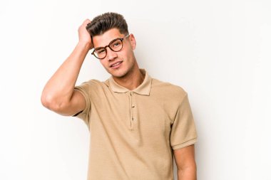 Beyaz arka planda izole edilmiş genç beyaz bir adam yorgun ve uykulu bir şekilde elini başının üstünde tutuyor..