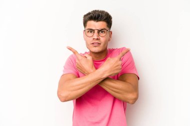 Beyaz arka plan noktalarında izole genç beyaz adam, iki seçenek arasında seçim yapmaya çalışıyor.