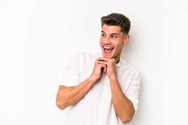 Beyaz arka planda izole edilmiş genç beyaz bir adam şans için dua ediyor, şaşırmış ve ağzını açıp önüne bakıyor..