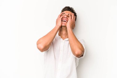 Beyaz arka planda izole olmuş genç beyaz bir adam ellerini başının üstünde tutarak neşeyle gülüyor. Mutluluk kavramı.