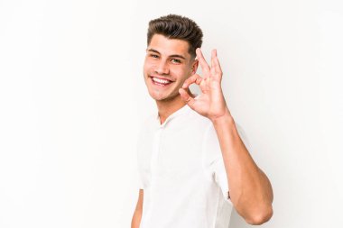 Beyaz arka planda izole edilmiş genç beyaz bir adam bir göz kırptı ve elleriyle iyi bir jest yaptı..