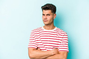 Kafkasyalı genç adam mavi arka planda izole edilmiş şüpheli, belirsiz, seni muayene ediyor..