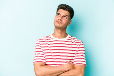 Mavi arka planda izole edilmiş genç beyaz adam tekrarlanan bir görevden yoruldu..