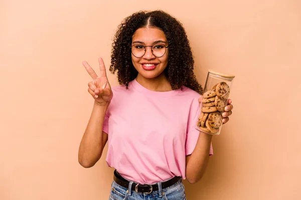 Young African American Woman Holding Cookies Jar Isolated Beige Background —  Fotos de Stock