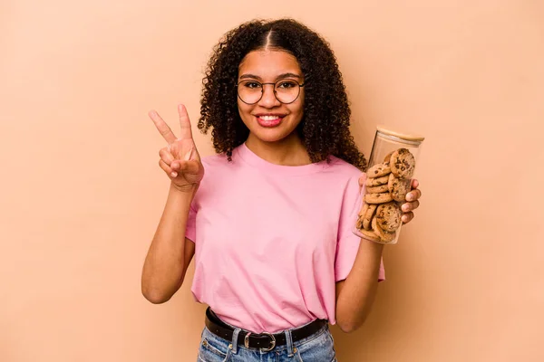 Young African American Woman Holding Cookies Jar Isolated Beige Background — Stockfoto