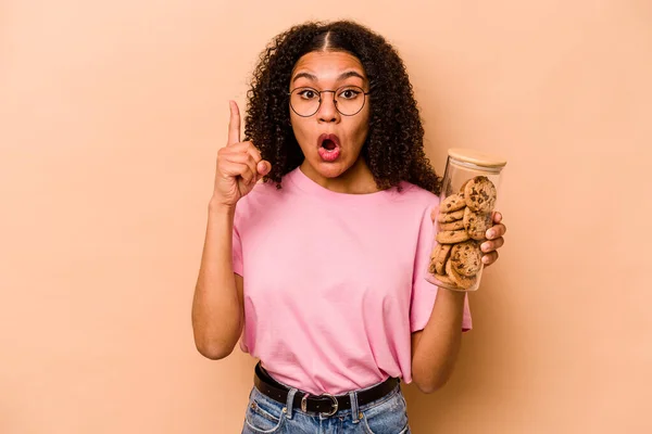 Young African American Woman Holding Cookies Jar Isolated Beige Background — Stockfoto