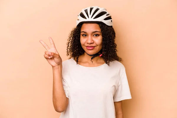 年轻的惊慌失措的女人 戴着一顶安全帽自行车 蓝色背景隔离着 手指头是二号 — 图库照片