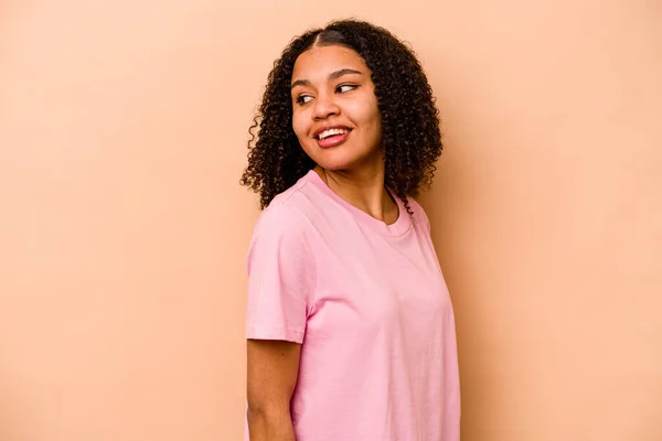 Joven Mujer Afroamericana Aislada Sobre Fondo Beige Mira Lado Sonriente — Foto de Stock