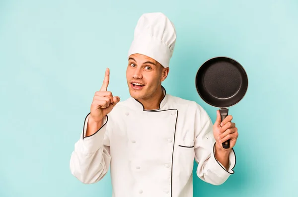 Young Caucasian Chef Man Holding Flying Pan Isolated Blue Background — Stockfoto