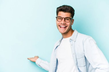 Mavi arka planda izole edilmiş beyaz bir genç hoş bir yüz ifadesi sergiliyor..