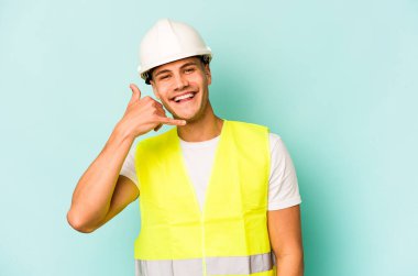 Genç beyaz adam mavi arka planda izole edilmiş. Parmakları olan bir cep telefonu hareketi gösteriyor..