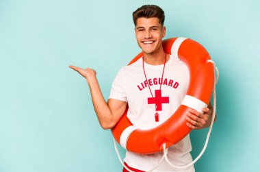 Young caucasian lifeguard isolated on blue background showing a copy space on a palm and holding another hand on waist.