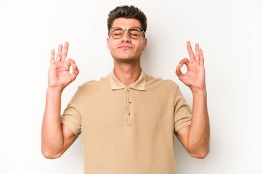 Beyaz arka planda izole edilmiş genç beyaz adam yoğun bir günün ardından rahatlıyor. Yoga yapıyor..