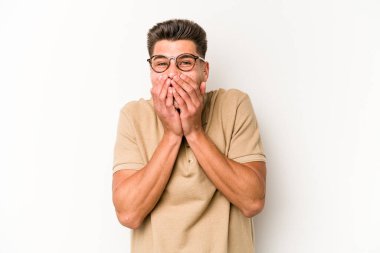 Beyaz arka planda izole olmuş genç beyaz bir adam bir şeye gülüyor, ağızlarını ellerle kapatıyor..