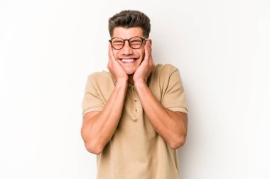 Beyaz arka planda izole edilmiş genç beyaz bir adam kulaklarını elleriyle kapatıyor..