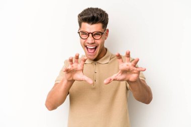 Beyaz arka planda izole edilmiş genç beyaz bir adam pençelerini kedi taklidi yaparken gösteriyor, agresif bir hareket..