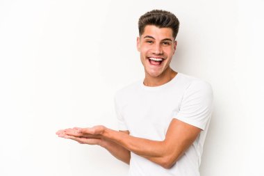 Beyaz arka planda izole edilmiş beyaz tenli genç bir adam palmiyesinde bir kopya alanı tutuyor..