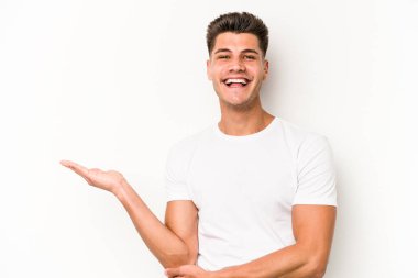 Beyaz arka planda izole edilmiş genç beyaz bir adam bir palmiye üzerinde fotokopi alanı gösteriyor ve belinde başka bir el tutuyor..