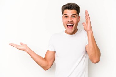 Beyaz arka planda izole edilmiş genç beyaz bir adam bir avuç içinde fotokopi alanı tutuyor, el üstünde tutuyor. Şaşırmış ve mutlu..